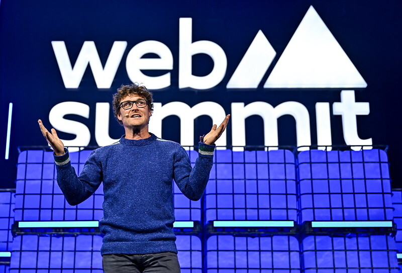 Paddy Cosgrave, CEO of Web Summit, speaking in front of Web Summit logo and blue background at Web Summit Vancouver