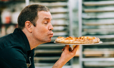 A man kissing a pizza