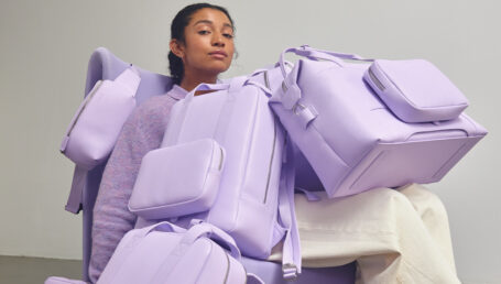 A woman carrying purple Monos luggage
