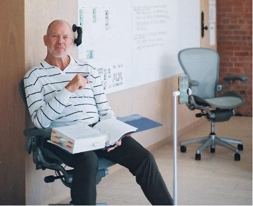 Chip Wilson sits in a chair with a book