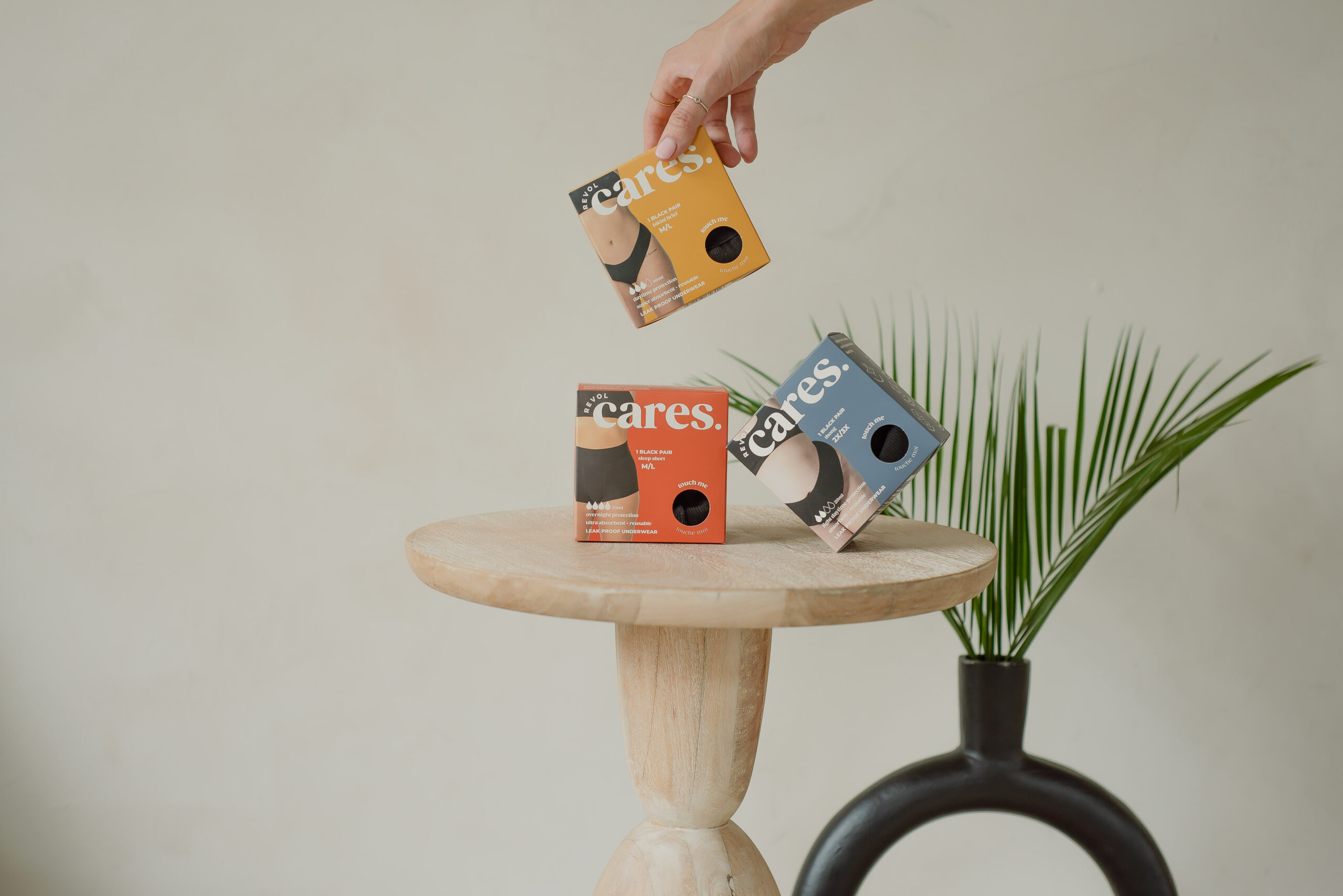 three boxes of Revol Cares products on a wooden table